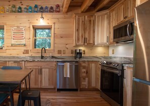 Eine Holzhütte mit einer Küche, inklusive Edelstahl-Kühlschrank, Backofen und Geschirrspüler.