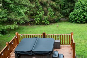 Eine Holzterrasse mit überdachter Sitzecke, einem kleinen Tisch und einem Lautsprecher.
