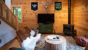 A wooden interior with a television, fireplace, and a sign that reads 'KEEP WILD'. - Howdybrook Basecamp | Hocking Hills Cabin (Laurelville)