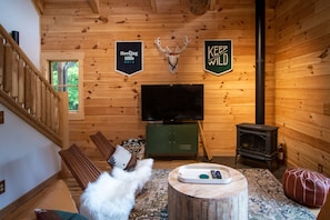 Ein Holzinnenraum mit Fernseher, Kamin und einem Schild mit der Aufschrift 'KEEP WILD'.