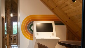 A modern interior with a wooden ceiling, a seating area with a chair, and a wall-mounted control panel. - Howdybrook Basecamp | Hocking Hills Cabin (Laurelville)