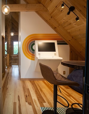 Ein modernes Interieur mit Holzbalkendecke, einer Sitzecke mit Sessel und einem an der Wand montierten Bedienfeld.