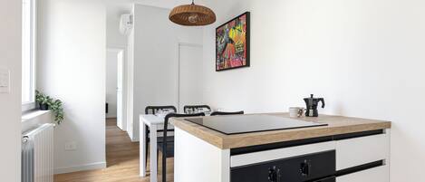 A modern kitchen with a central island, black appliances, and a dining area with chairs.