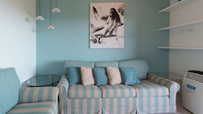 Ein Zimmer mit einer gestreiften Couch, einem kleinen Tisch und einem an der Wand befestigten Luftreiniger.
