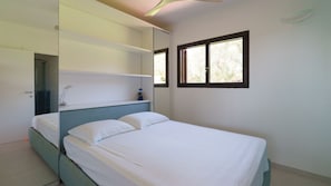 Ein Schlafzimmer mit Bett, Nachttisch, Spiegel und Fenster.