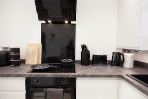 Eine moderne Küche mit einem schwarzen Induktionskochfeld, einem Toaster, einer Kaffeemaschine und einem Wasserkocher.