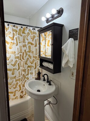 A bathroom with a white sink, a mirror, and a shower curtain with a cowboy boot pattern.
