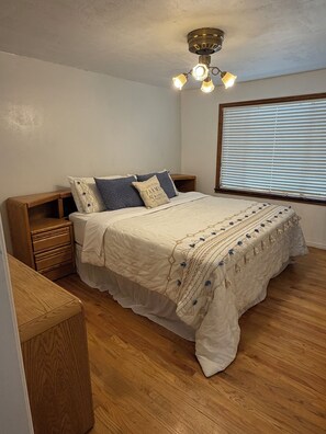 A bedroom with a bed, wooden nightstand, and a ceiling fan.