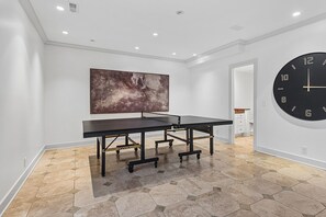 A room with a ping pong table, a large abstract painting, and a round wall clock.