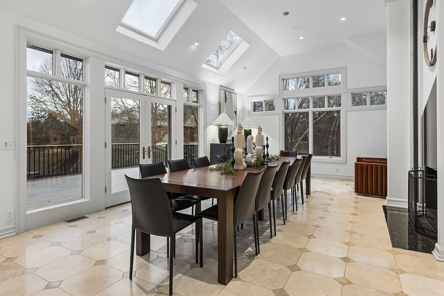 A spacious dining area with a long table, multiple chairs, and a modern chandelier.