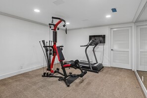 A home gym with a stationary bike, a bench press, and a cable machine.