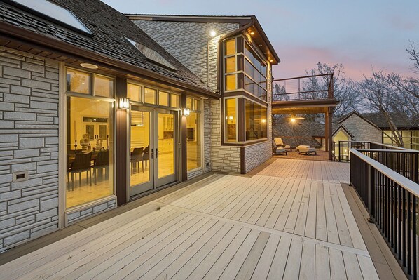A modern house with a deck, stone facade, and large windows.