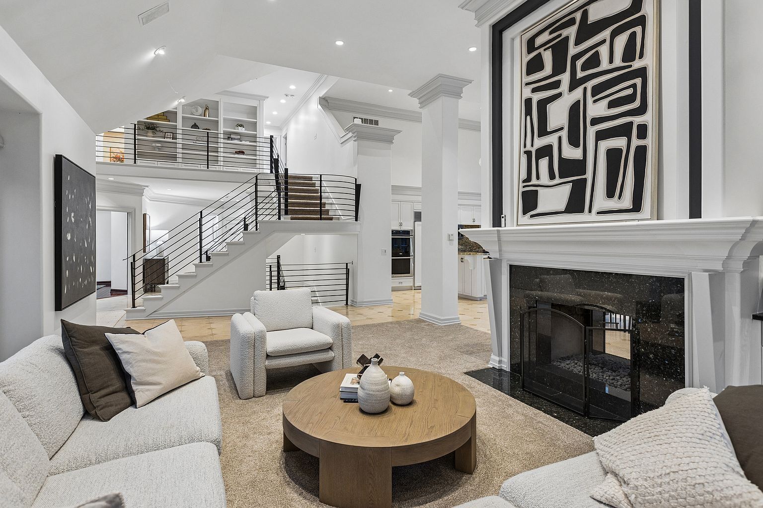 A spacious living room with a fireplace, a staircase, and a modern design.