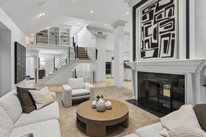 A spacious living room with a fireplace, a staircase, and a modern design.