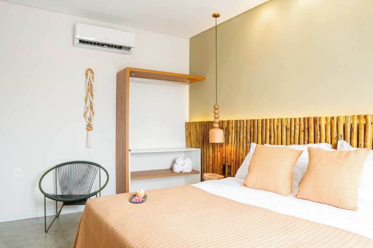 Una moderna camera d'albergo con un letto, una sedia, uno scaffale e una lampada a sospensione.