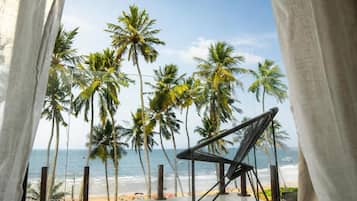 A beach view with palm trees and a chair.