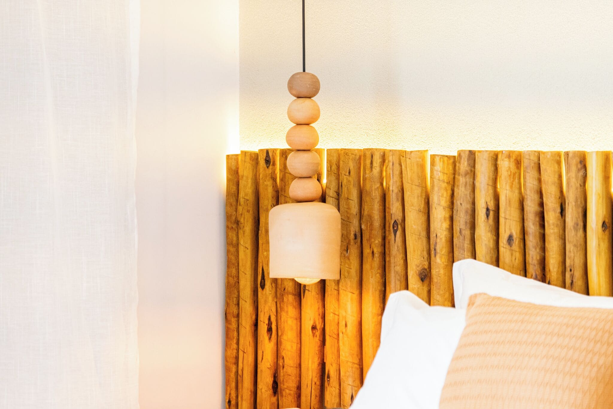 A bed with a wooden headboard and a hanging light fixture.