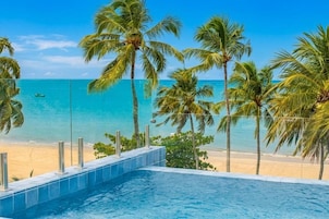 Una piscina con vista a una playa y palmeras.