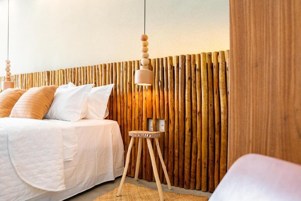 Un dormitorio con cama, mesita de noche y una pared con listones de madera verticales.