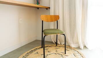 A chair with a wooden backrest and green seat, placed on a woven floor mat.