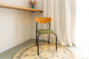 Una silla con respaldo de madera y asiento verde, sobre un tapete tejido.