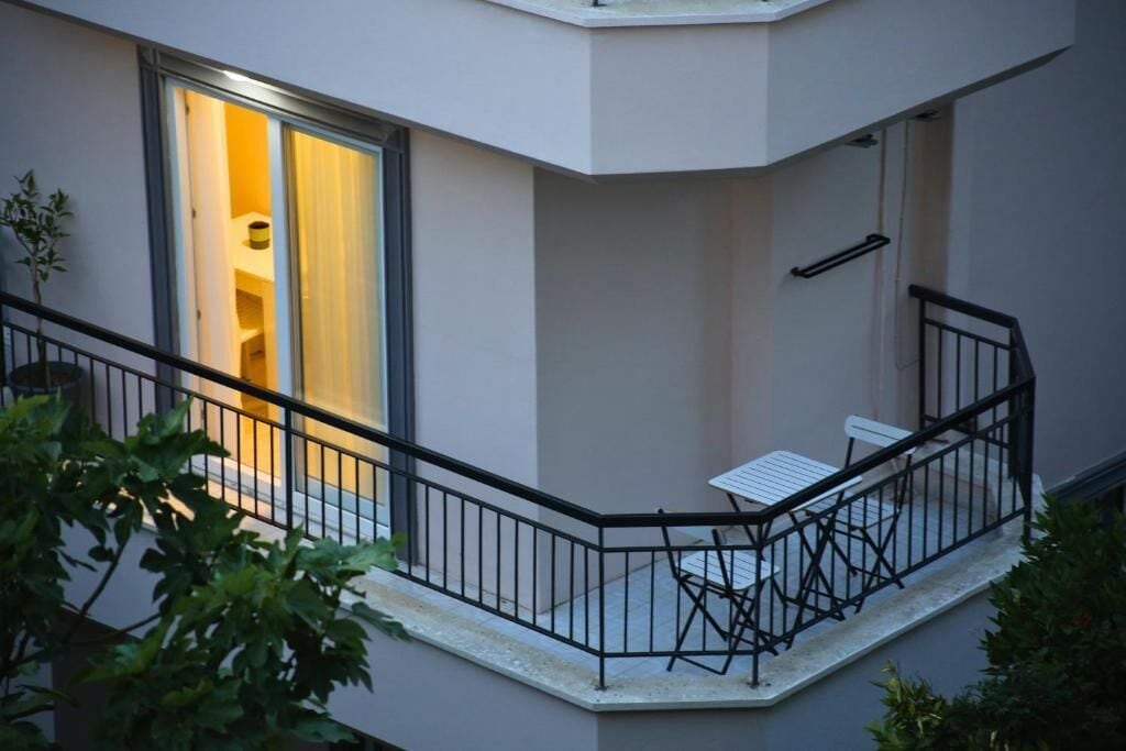 A balcony with a table and chairs, a railing, and a door leading to an interior space.