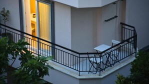 A balcony with a table and chairs, a railing, and a door leading to an interior space. - Lemon Garden (Antalya)