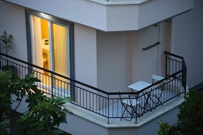 A balcony with a table and chairs, a railing, and a door leading to an interior space.