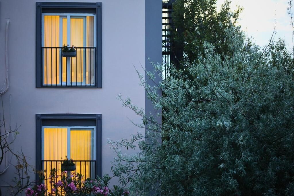 A building with two windows, each with a black frame and a hanging planter.