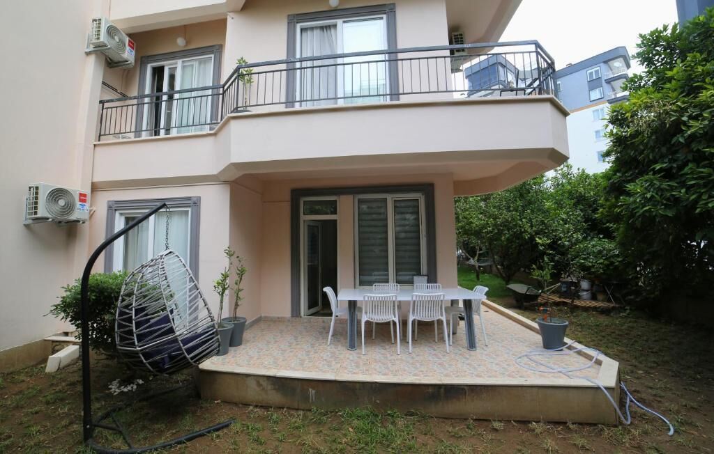 A two-story building with a balcony, outdoor seating area, and a hanging chair.