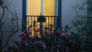 A building with two windows, each with a black metal railing and a hanging planter. - Lemon Garden (Antalya)