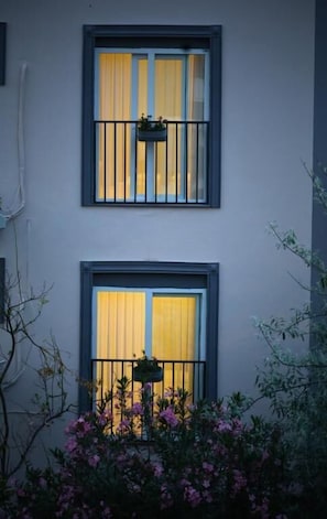 A building with two windows, each with a black metal railing and a hanging planter.
