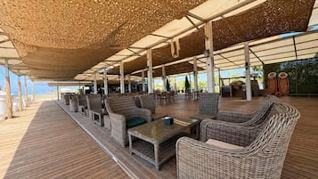 Uma área de estar ao ar livre com mobiliário de vime e um deck de madeira.
