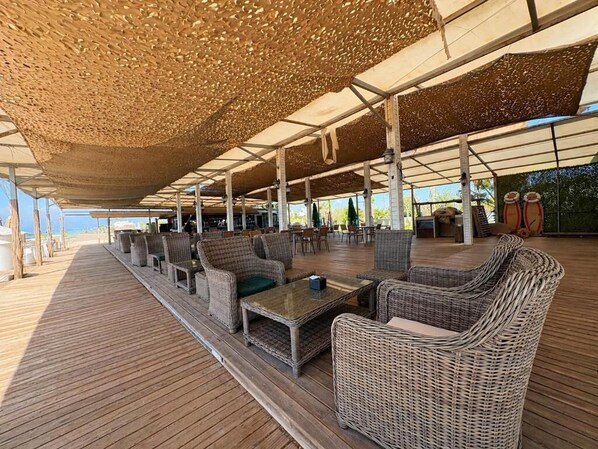Un espacio de estar al aire libre con muebles de mimbre y una terraza de madera.