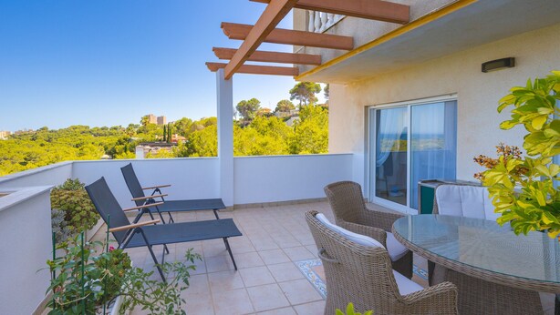 A balcony with outdoor furniture, a glass table, and a view of greenery and buildings. - Victoria Playa Campoamor (Orihuela)