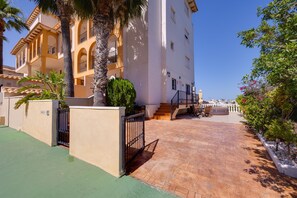 Ein Wohngebäude mit Innenhof, einer Treppe zu einer oberen Ebene und Blick auf das Meer im Hintergrund.