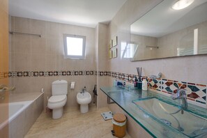 Ein Badezimmer mit einem Waschbecken aus Glas, einer Toilette, einem Bidet und einer Badewanne.