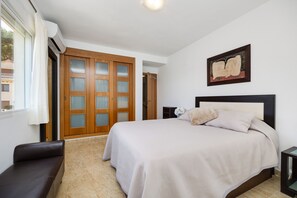 Ein Schlafzimmer mit einem Bett, einer Bank, einem Gemälde und einer Tür mit geätzten Glasscheiben.
