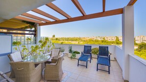 A balcony with wicker furniture, a glass table, and potted plants. - Victoria Playa Campoamor (Orihuela)