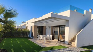 Ein modernes Haus mit Terrasse, Treppe und gepflegtem Rasen.