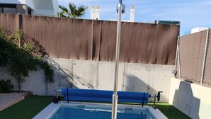 Ein rechteckiger Pool mit einem Metallstab in der Mitte, umgeben von künstlichem Rasen und einer Betonplattform.