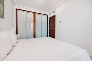 A bedroom with a bed, a nightstand, a wardrobe, and a door. - Apartment Royal Park Lomas Cabo Roig (Orihuela)