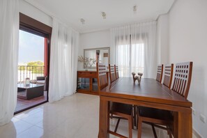 A dining area with a wooden table and chairs, a glass cabinet, and a view of the outdoors through a sliding door. - Apartment Royal Park Lomas Cabo Roig (Orihuela)