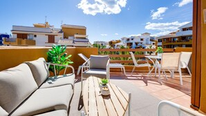 A rooftop terrace with outdoor furniture, a potted plant, and a view of surrounding buildings. - Recoleta Penthouse Punta Prima (Torrevieja)