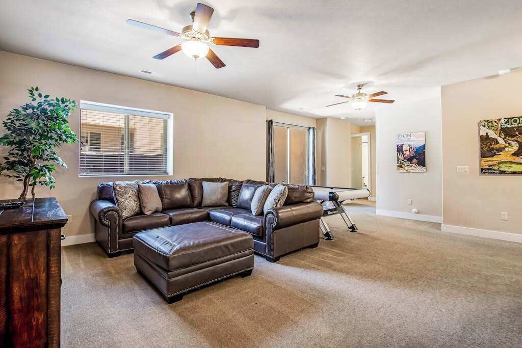 A living room with a sectional sofa, a coffee table, a potted plant, and ceiling fans.