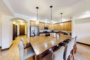 Una cocina moderna con una isla grande, armarios de madera e iluminación colgante.