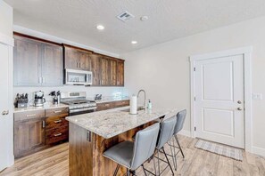 A kitchen with wooden cabinets, a microwave, a stove, and a marble countertop. - 4BR desert townhouse with game room, bikes, & AC (Washington)