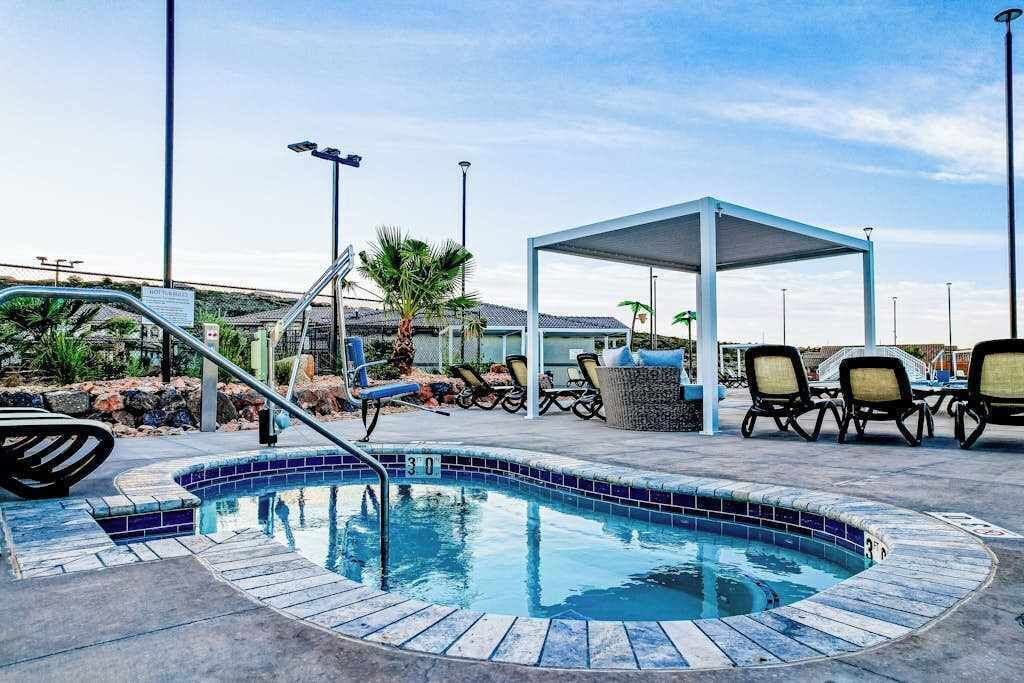 A swimming pool with a sunshade, lounge chairs, and a covered seating area.