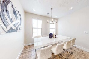 A modern kitchen with a large island, white chairs, and a chandelier. - 4BR desert townhouse with game room, bikes, & AC (Washington)