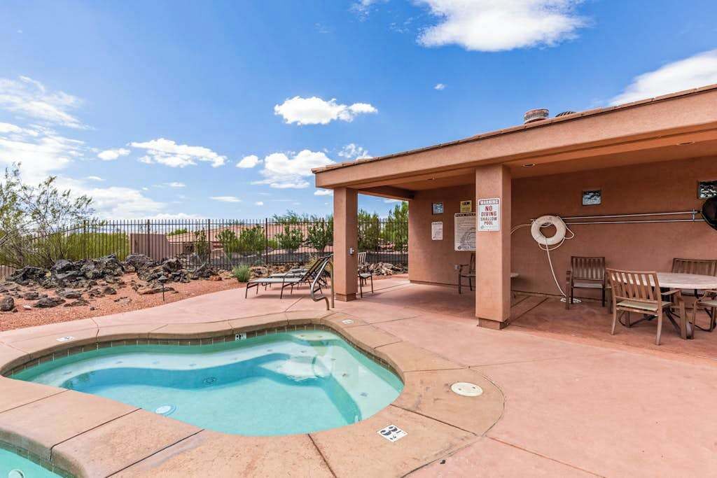 A swimming pool with a hot tub, outdoor seating, and a covered area with a table and chairs.